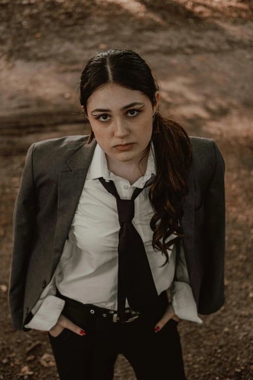 a portrait of a person styled as an anime sword fighter, wearing traditional-inspired layered outfit, wide sleeves, structured silhouette, bold shadows, and strong directional lighting