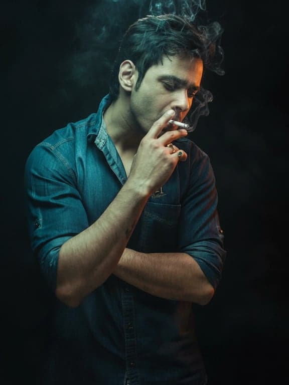 An intense cinematic portrait of a man, defined by a sharp teal and orange color split, dramatic low-key lighting creating deep shadows, professional photography, studio backdrop.