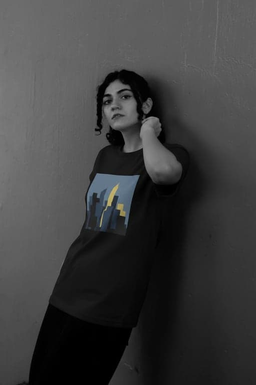 a portrait of a person transformed with a refined T-shirt design presentation featuring a single flat illustration placed inside a rectangular print area on the chest, limited color palette, no texture or pattern fill, clean borders, accurate fabric interaction, consistent lighting, and natural body posture