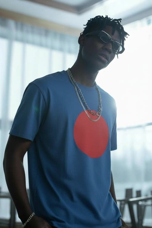 a portrait of a person edited to display a minimalist T-shirt graphic design featuring a single geometric shape such as a circle, square, or triangle, solid fill color, no gradients, no patterns, centered placement on the chest, clean edges, natural fabric interaction, and realistic shirt texture