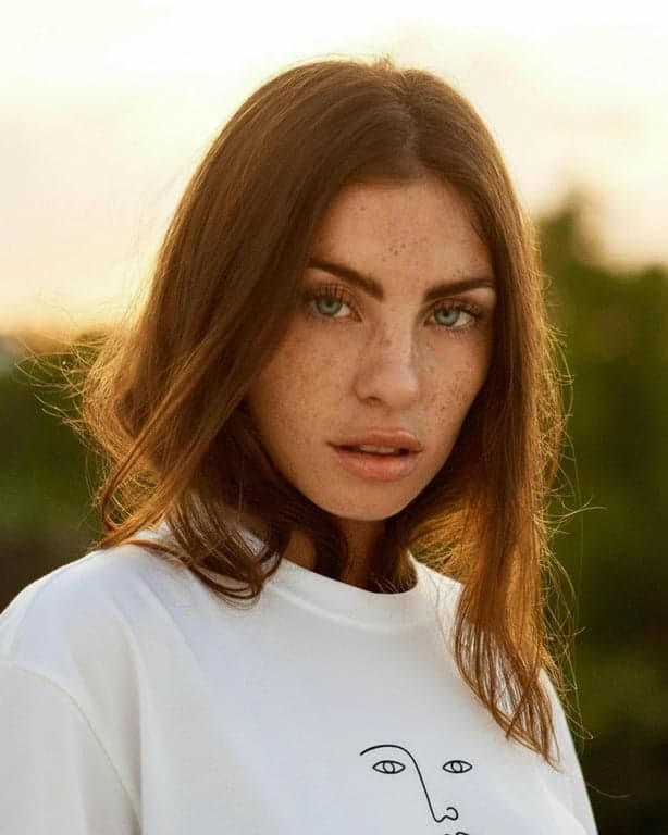 a portrait of a person transformed to wear a T-shirt with a clear illustrated graphic of a simple line-art object such as a flower, star, or abstract face, drawn with thin black outlines, flat illustration style, no background texture inside the print, centered on the chest, with crisp edges, realistic print contrast, natural fabric folds, and consistent lighting