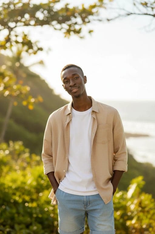 a portrait of a person styled with vacation summer outfit elements, flowing dresses or relaxed shirts and shorts, lightweight fabrics, open silhouettes, warm sunlit tones, relaxed confident posture, and airy background