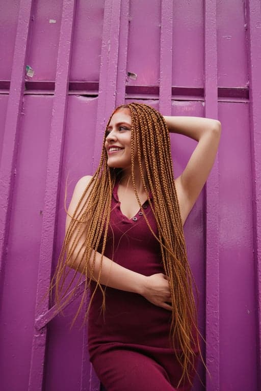 A realistic AI-generated portrait of a woman with long, neat goddess braids, some strands loose, realistic flyaways, soft natural lighting.