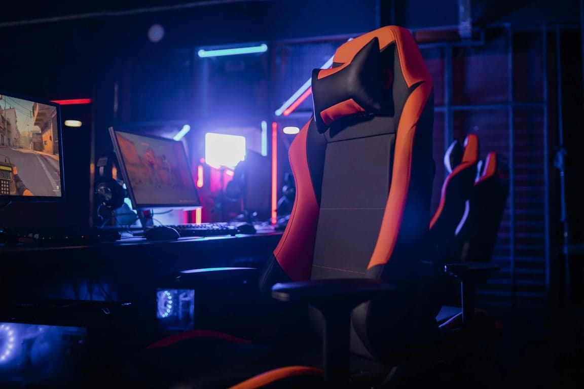a hyper-realistic chicken nugget sitting in a gamer chair, staring at a computer screen, neon lighting, detailed but absurd scene.