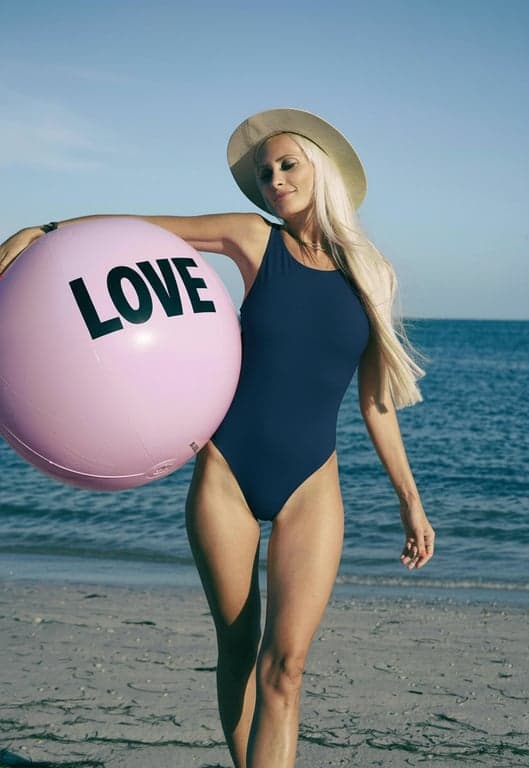 a portrait of a person edited to wear a different bathing suit style, focusing on clean swimsuit lines, accurate fabric-to-skin transitions, preserved body proportions, relaxed pose, and simple background