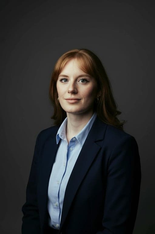 a portrait of a person wearing classic business attire, photographed in a studio-like environment with neutral backdrop, even facial illumination, realistic texture preservation, restrained color grading, and a composed corporate headshot aesthetic