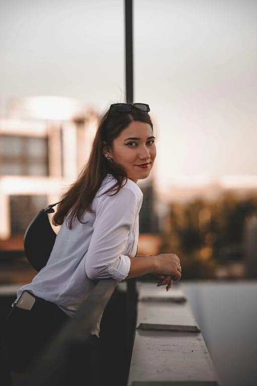 a portrait of a person with increased hair fullness achieved by lifting roots and reinforcing strand density along existing layers; keep original haircut, hairline, and proportions unchanged; avoid helmet-like silhouettes; preserve flyaways and fine strands; no changes to face, posture, or background; result should resemble naturally dense hair