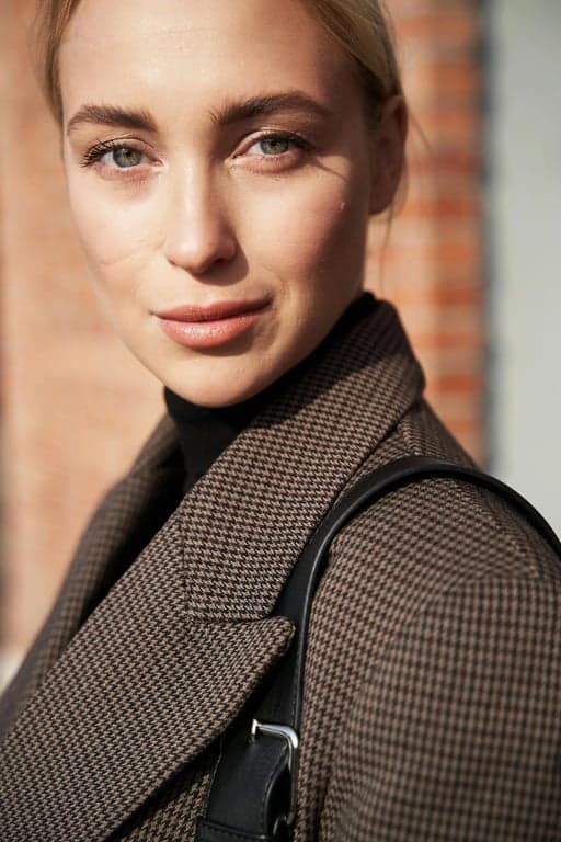 a portrait of a person styled with subtle 70s vintage outfit details, clean flared cuts, simple retro tops, muted warm tones, balanced outfit proportions, relaxed stance, and even lighting