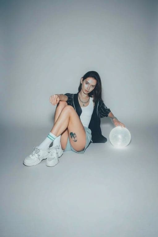 A cool tone filtered portrait of a woman, porcelain-like skin with blue undertones, silver jewelry highlights, soft grey backdrop, ethereal and calm mood.