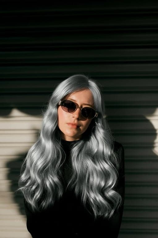 a portrait of a person transformed with silver hair color, featuring cool gray tones, metallic highlights, subtle blue undertones, preserved strand detail, and realistic reflective shine