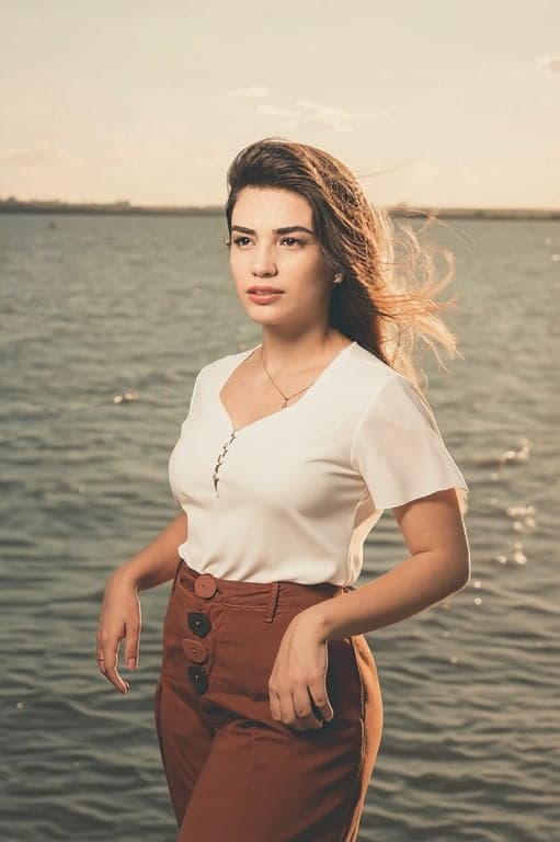 a portrait of a person edited to dramatically reduce waist width by aggressively pulling the waist inward on both sides, while keeping hip width unchanged or visually wider, creating a very high waist-to-hip ratio and an unmistakable hourglass silhouette with an obvious before-and-after difference